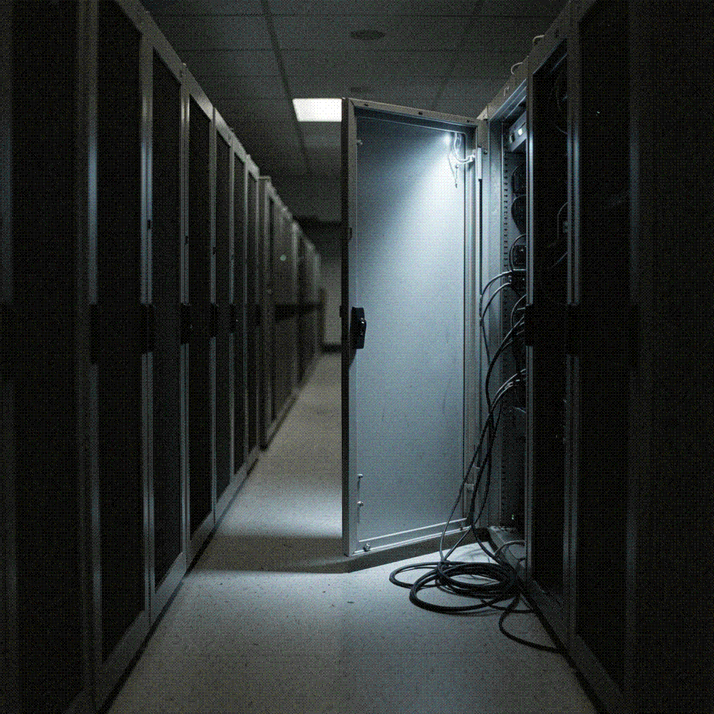 Dark server-room aisle with one cabinet door standing ajar, cold blue light spilling across the floor
