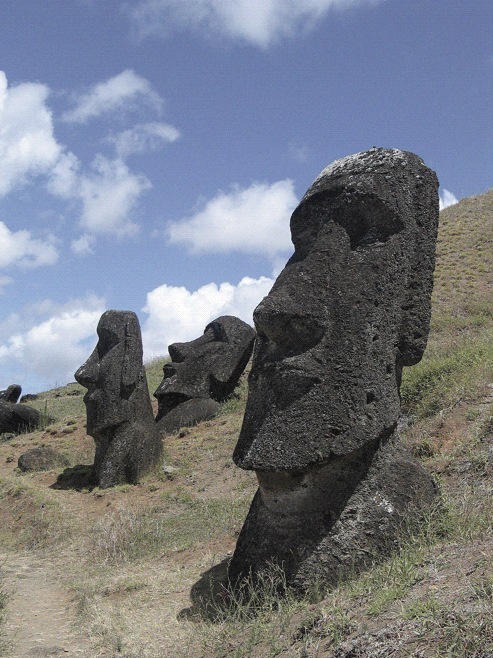Moai standing on the grassy slope of the Rano Raraku quarry on Rapa Nui under a clouded sky