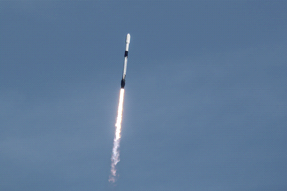 A Falcon 9 rocket climbing on a column of flame at night, carrying a batch of Starlink satellites to orbit.